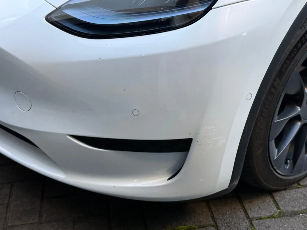 Minor scratches and scuff marks on a white car front bumper requiring professional scratch repair in Sydney."